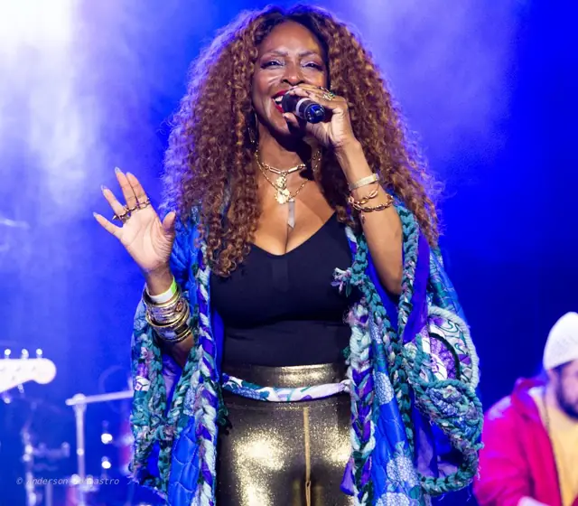 Kandace Lindsey singing in a blue patterned jacket under stage lights