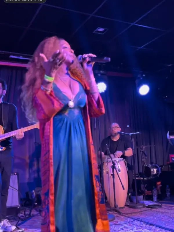 Kandace Lindsey singing in a long blue and orange dress